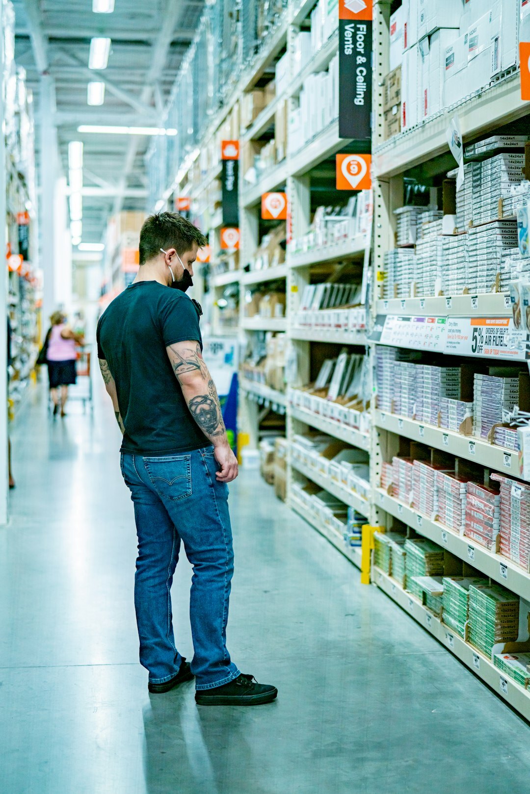 Warehouse worker inspecting packaged consumer goods on an industrial shelf